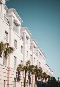 Bright modern building facade with palm trees against a clear blue sky.